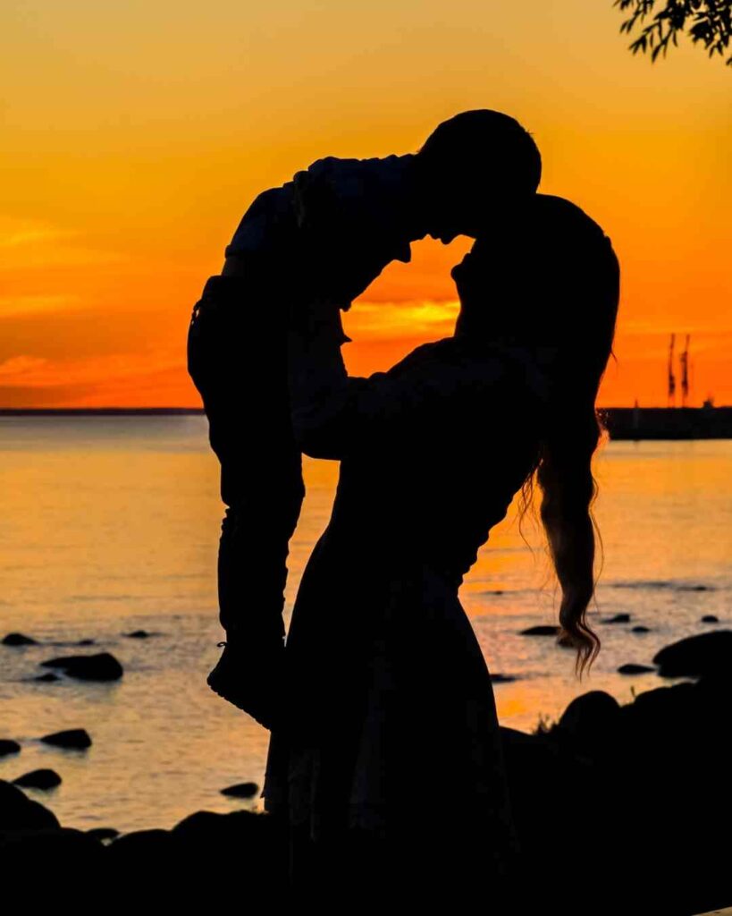 Sunset silhouette of mother carrying son